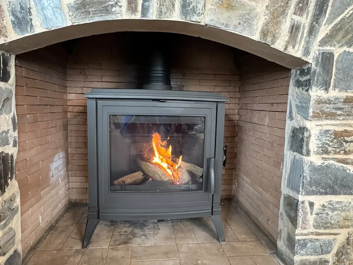 Estufa de leña instalada en chimenea revestida de piedra